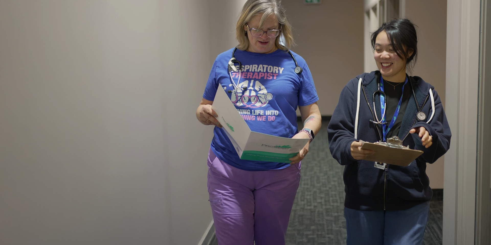 Two ProResp RTs walking ddown a hall with documents talking smiling