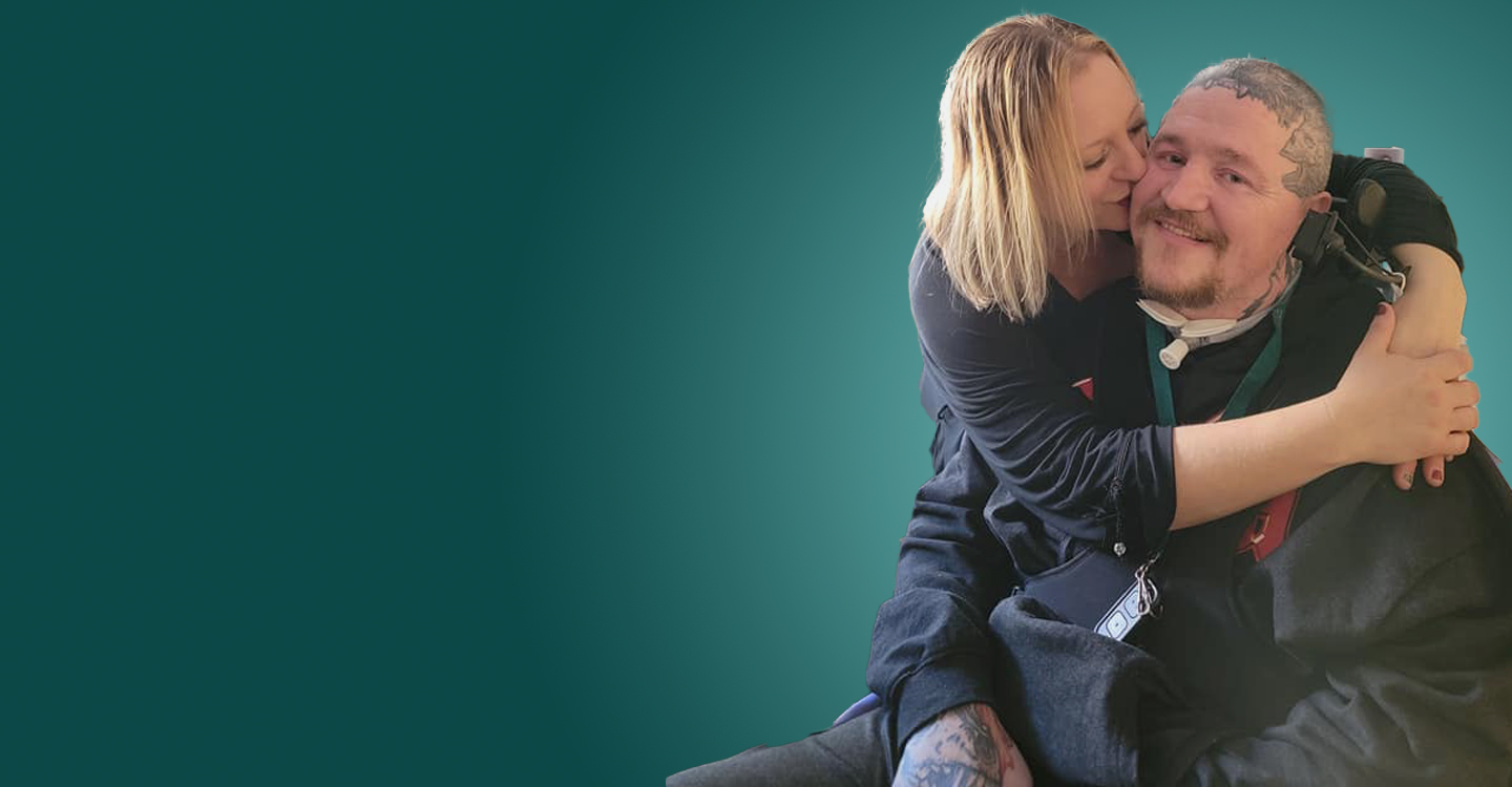 Man in Wheelchair being hugged and kissed by woman