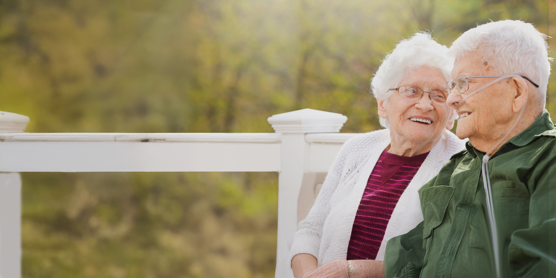 two seniors sitting outside one with nasal cannual