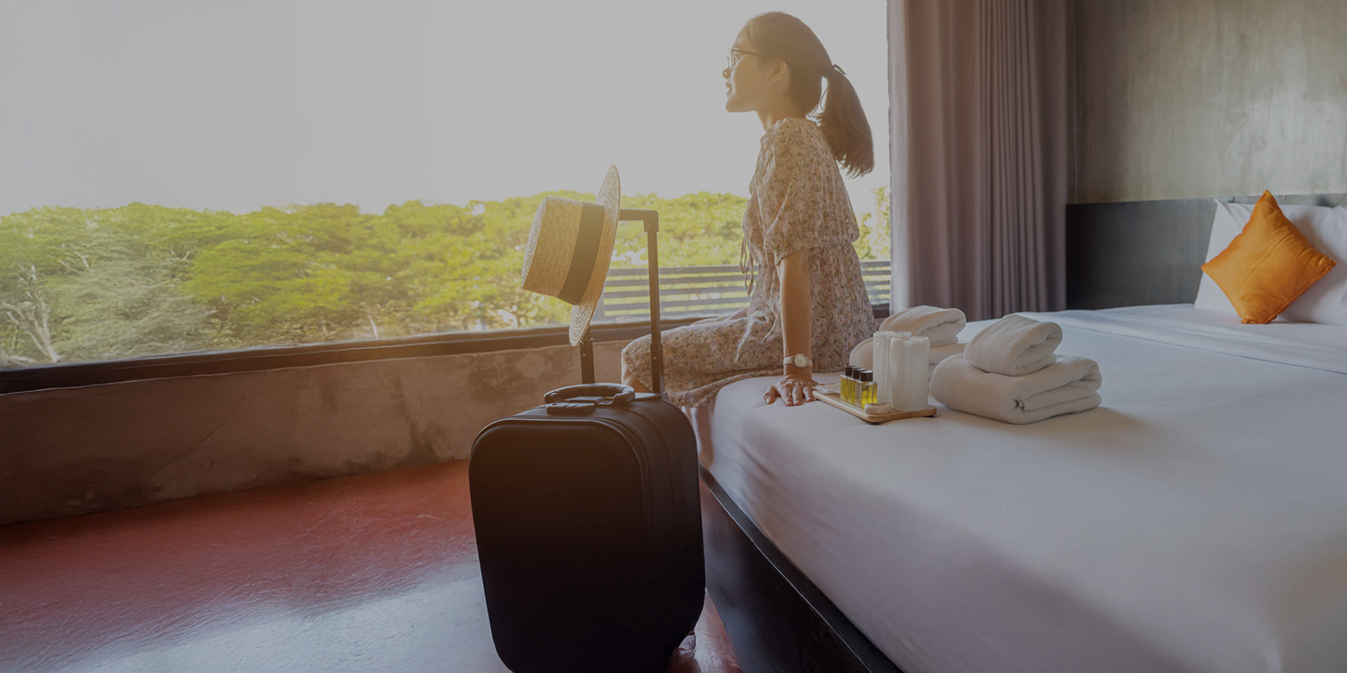 Woman sitting on bed with a suitcase